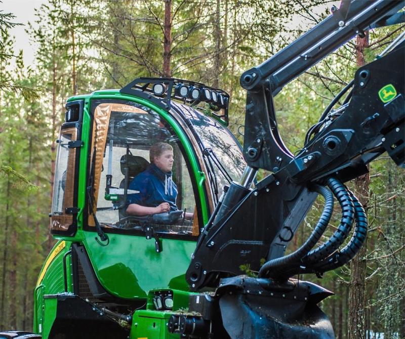 Kille som kör en grävskopa i skogen