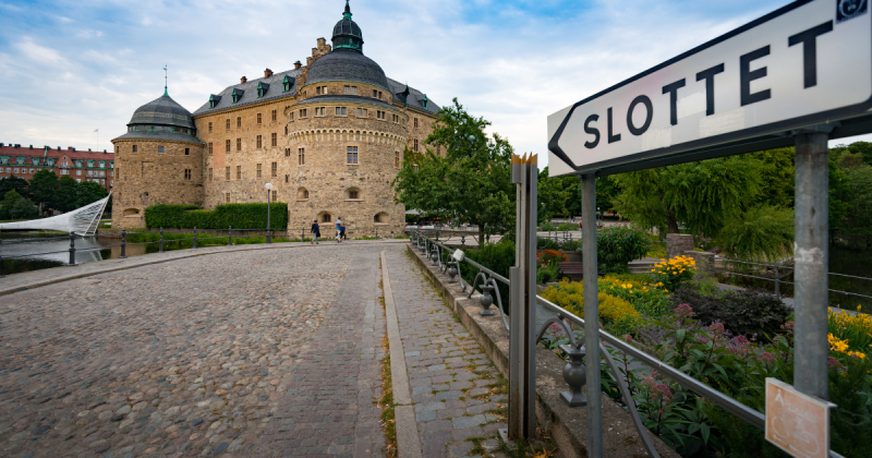 Bilden visar en gågata i Örebro med en skylt med texten slottet på och Örebro slott syns i bakgrunden